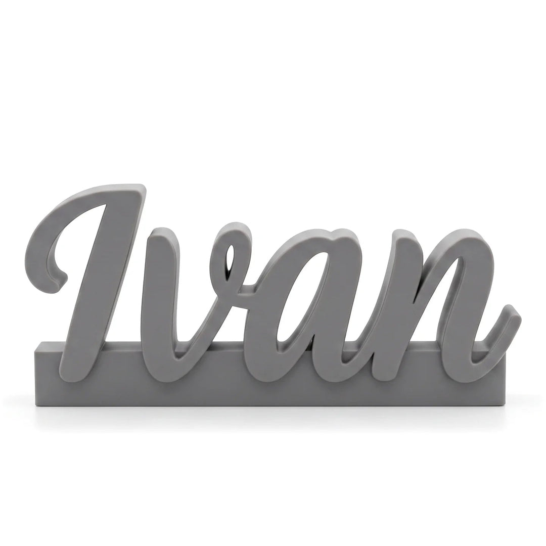 Marcasitios personalizado con el nombre Ivan en caligrafía ligada sobre base, en gris piedra