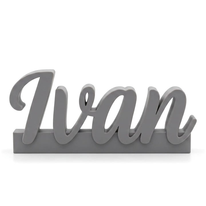 Marcasitios personalizado con el nombre Ivan en caligrafía ligada sobre base, en gris piedra
