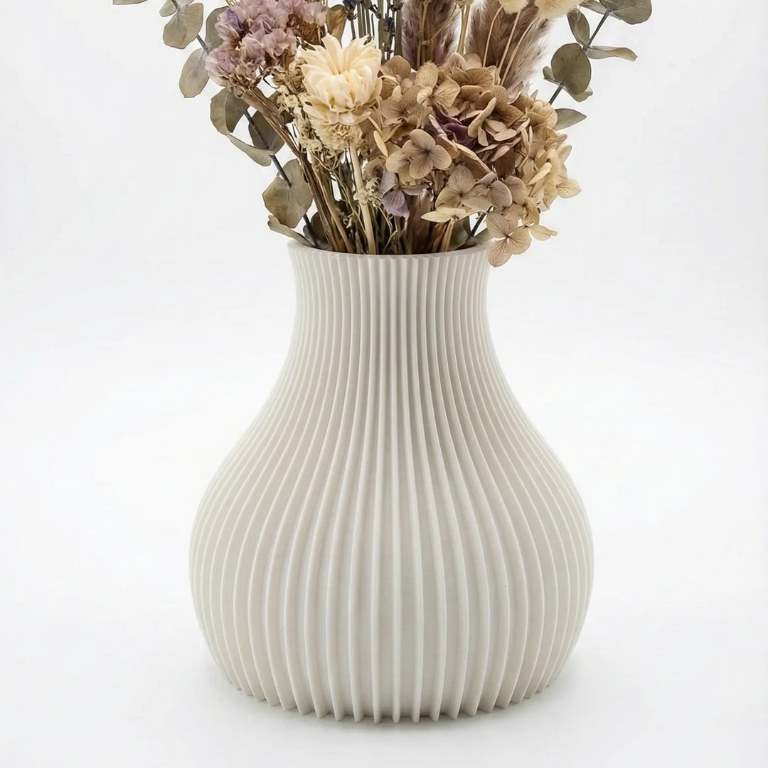 arrón decorativo blanco con textura de estrías verticales y diseño orgánico sobre una mesa de madera con flores secas.