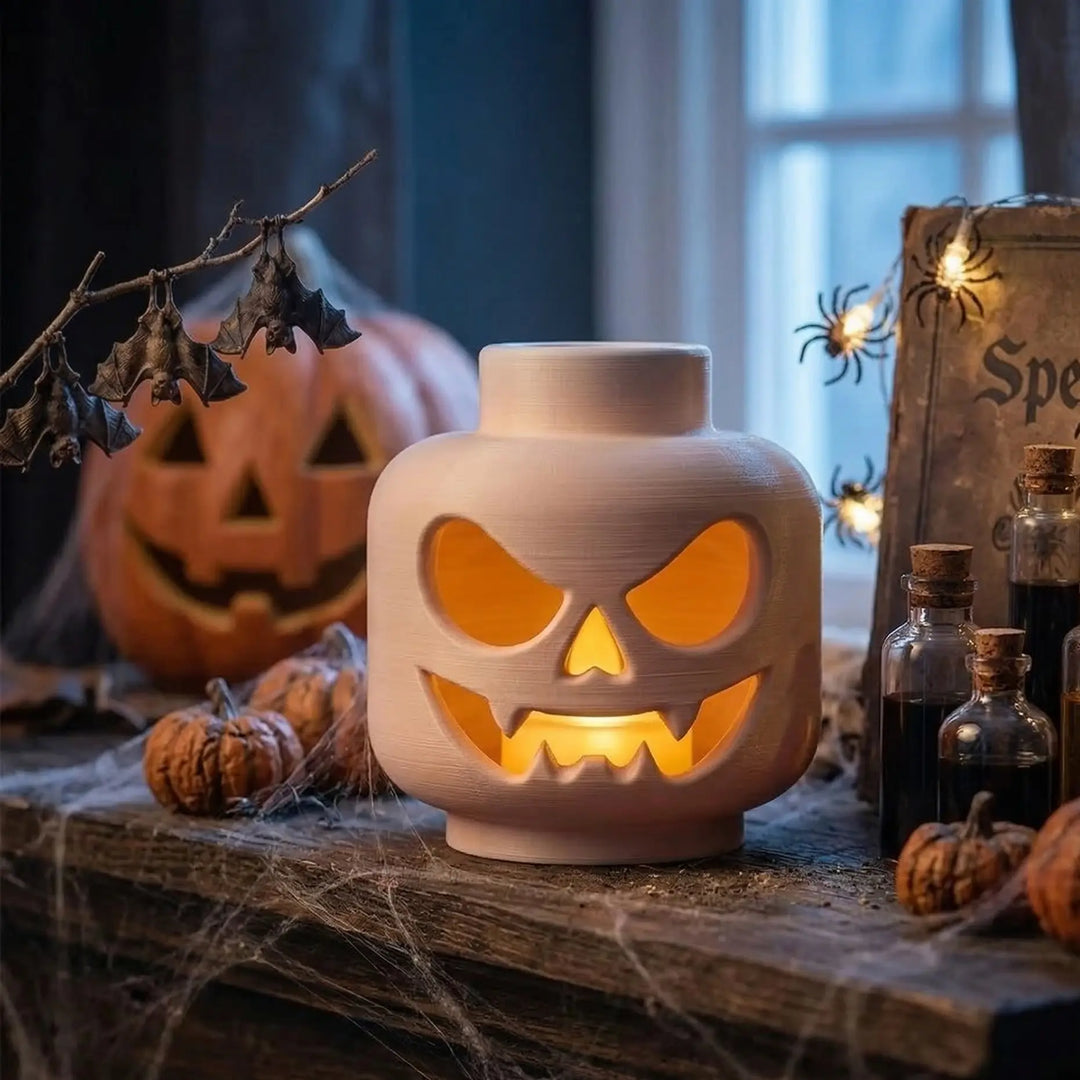 Lámpara decorativa con forma de cabeza de bloque y rostro de Halloween iluminado desde el interior en polímero mate.
