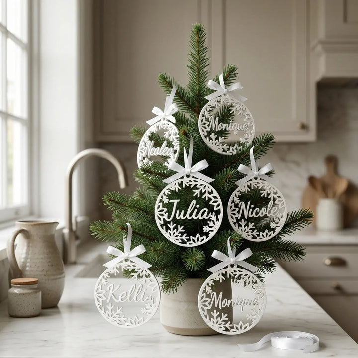 Gepersonaliseerde kerstversieringen met namen Julia en Monique in witte matte afwerking met sneeuwvlokkenkrans.