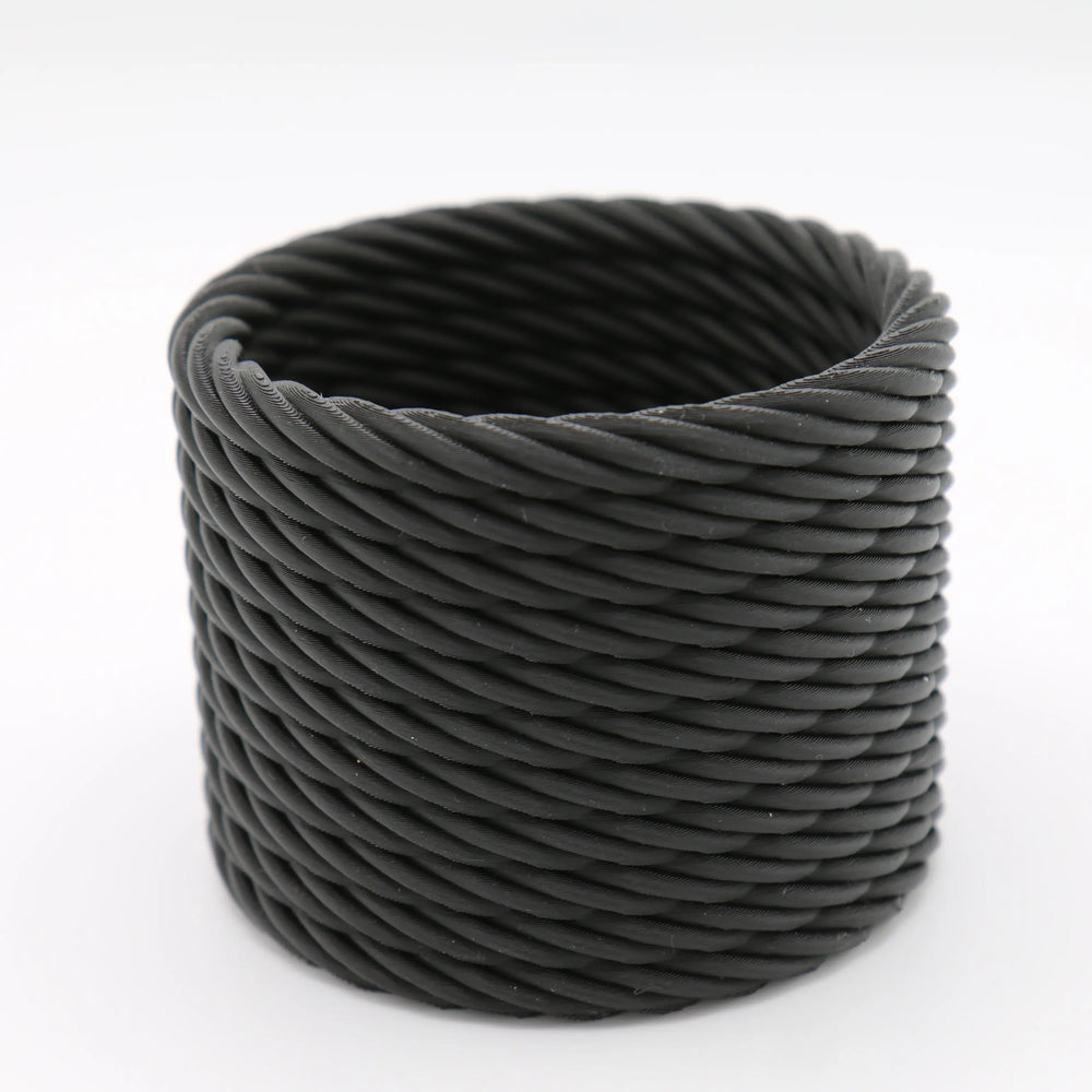 Macetero cilíndrico negro con textura de cuerda trenzada en relieve sobre fondo blanco.