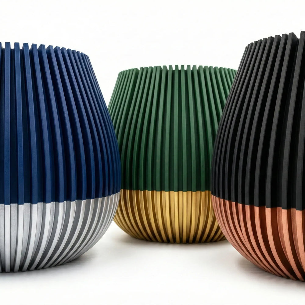 Primer plano de macetero con textura de líneas verticales, mitad superior negra y base color cobre satinado.