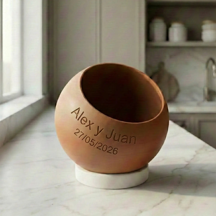 Personalisierbarer kugelförmiger Blumentopf in Wunschfarbe mit diagonaler Öffnung und rundem weißem Sockel, individuell gestaltet mit gravierten Namen und Daten auf der Seite.