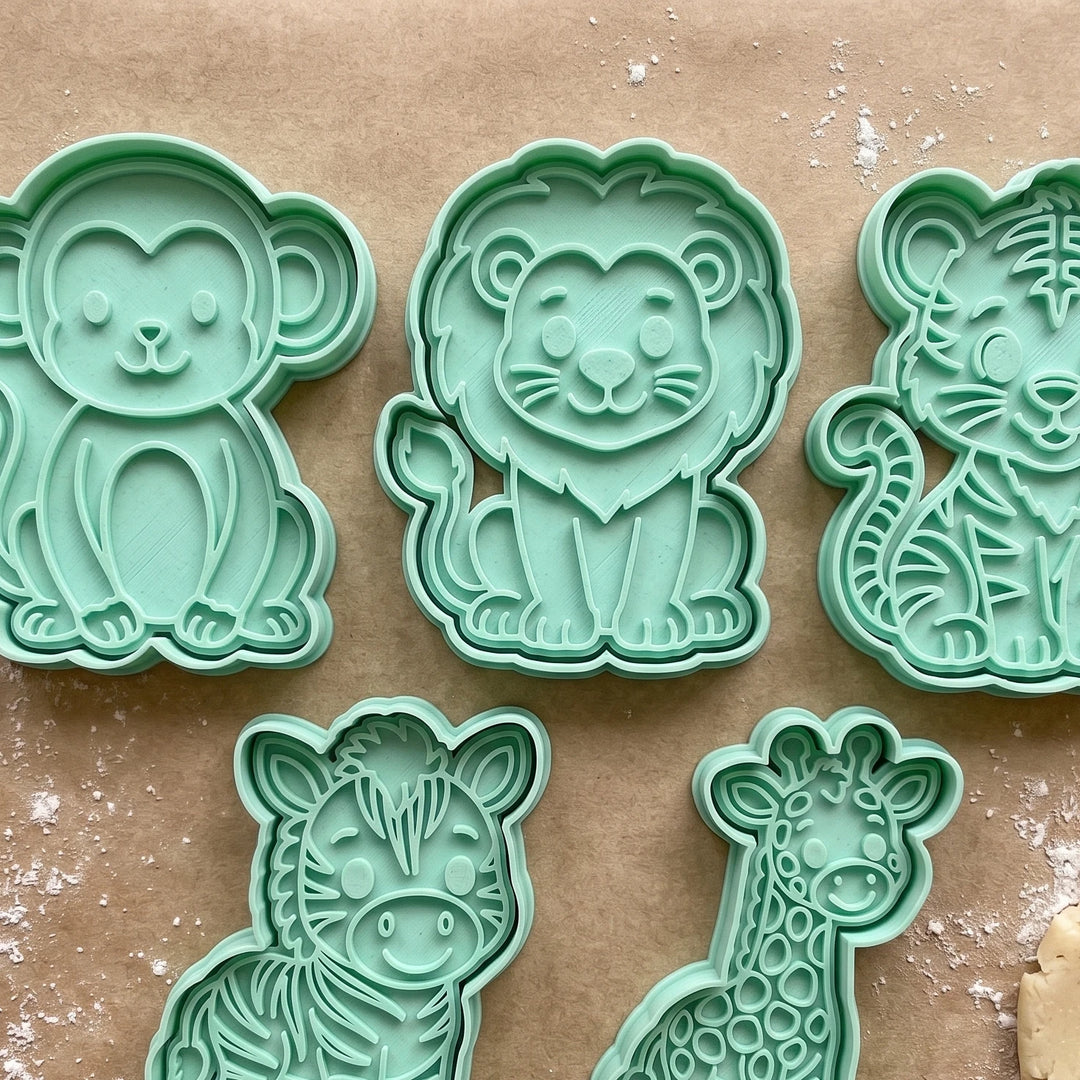 Cortadores de galletas de animales de la jungla en color verde menta sobre papel de horno.