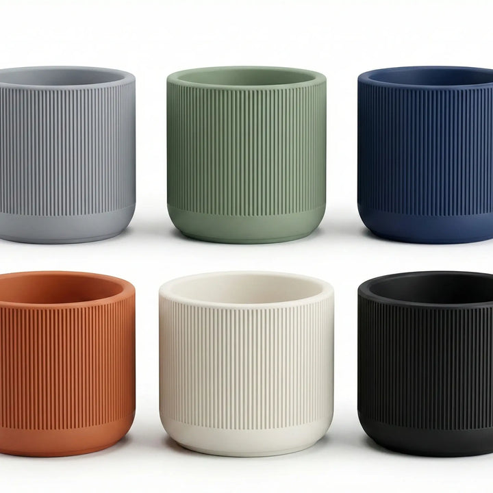 Set de 6 macetas texturizadas en colores gris, verde, azul, terracota, crema y negro, mostrando acabado mate y diseño estriado.