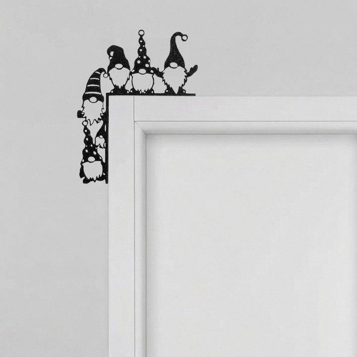 Tür-Eckendekoration mit der Silhouette von fünf folkloristischen Gnomen, angebracht an der oberen Ecke eines weißen Türrahmens.