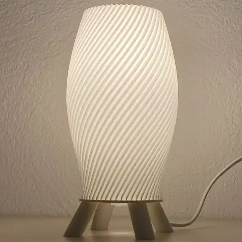 Cremefarbene Helix-Design-Tischlampe mit dunklem Stativfuß in Holzoptik auf weißer Oberfläche.