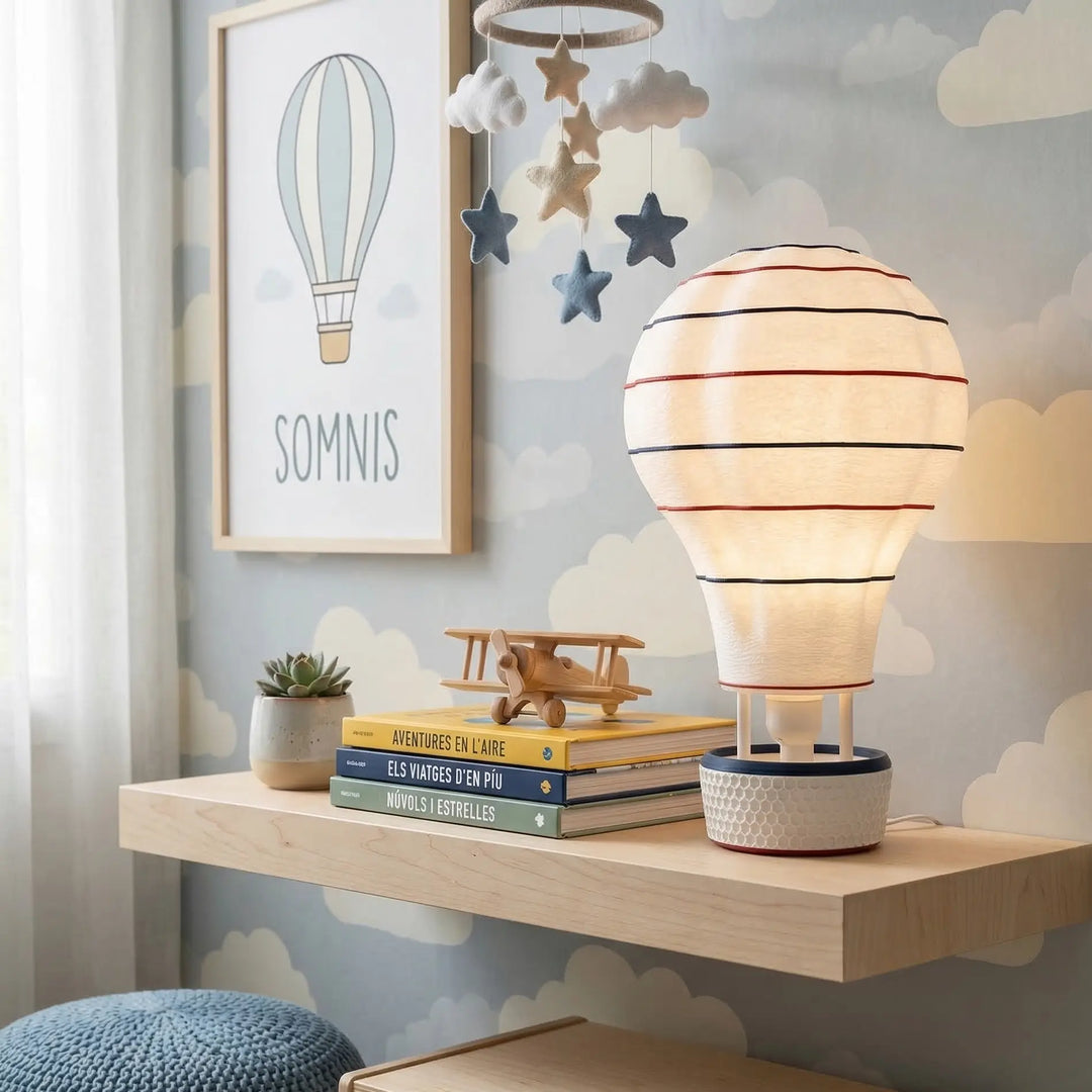 Lámpara decorativa con forma de globo aerostático emitiendo luz cálida en un estante de madera clara.
