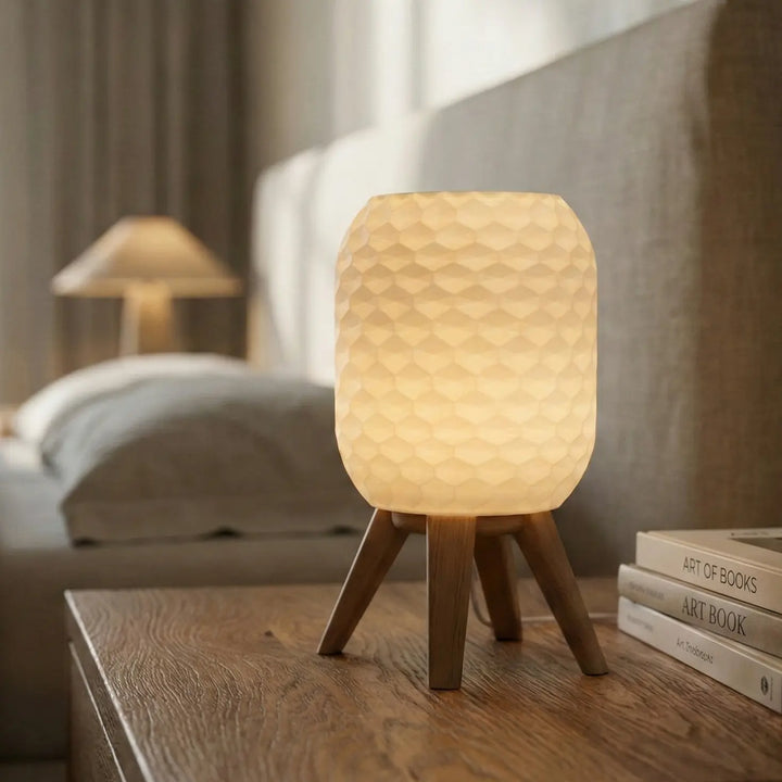 Zylindrische Tischlampe mit weißem Schirm in Hexagonal-Struktur und matt granatroter Stativ-Basis.