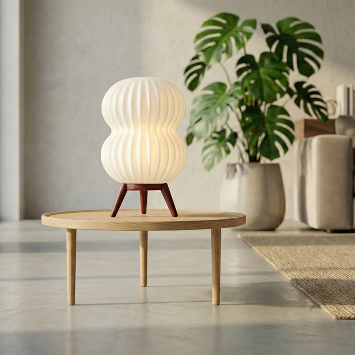 Lámpara de mesa con diseño orgánico y patas efecto de madera. Pantalla texturizada para una luz difusa y cálida. Ideal para dormitorio o salón nórdico.