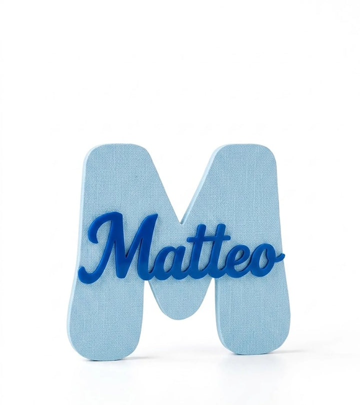Marcasitios letra inicial M volumétrica azul claro con nombre Matteo en script azul oscuro superpuesto sobre fondo blanco