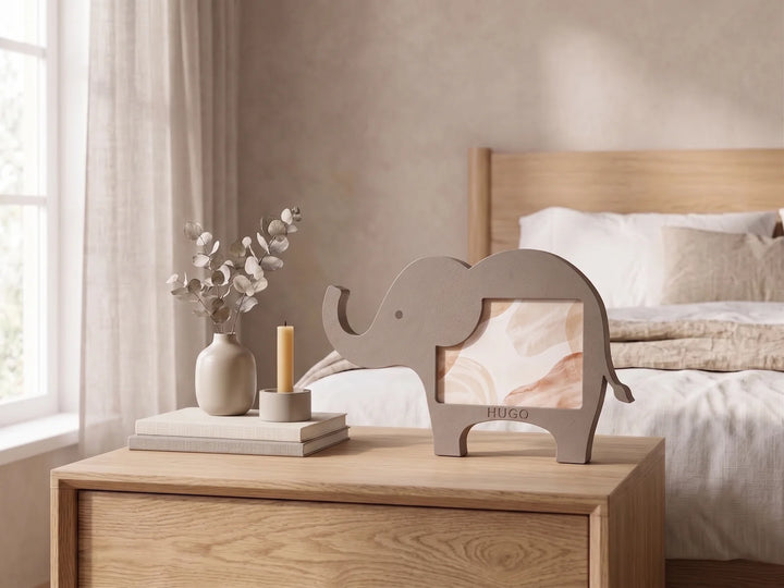 Marco de fotos infantil con forma de elefante y el nombre Hugo sobre una mesita de noche