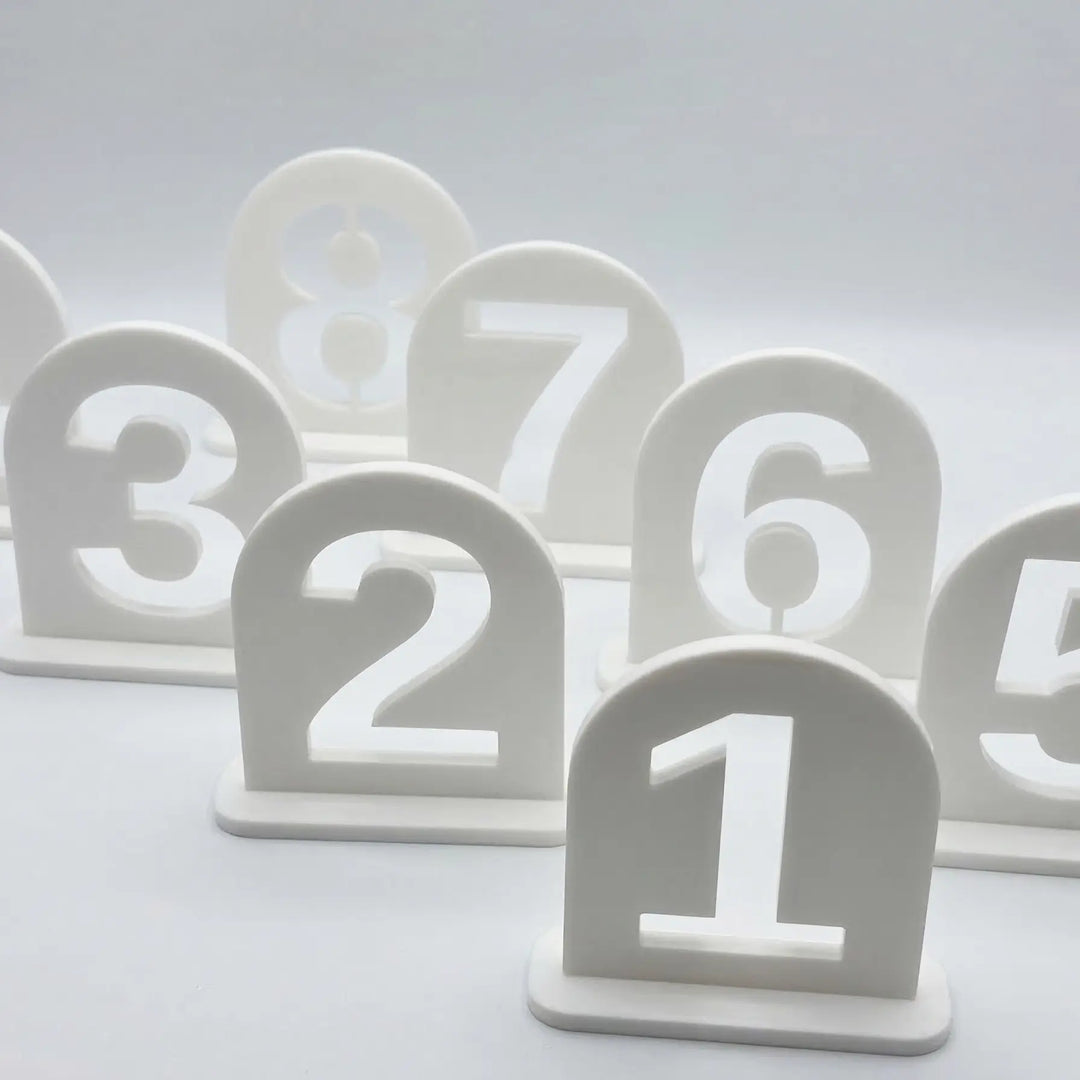 Ensemble de numéros de table en arche avec finition mate démontrant la précision de la découpe géométrique.