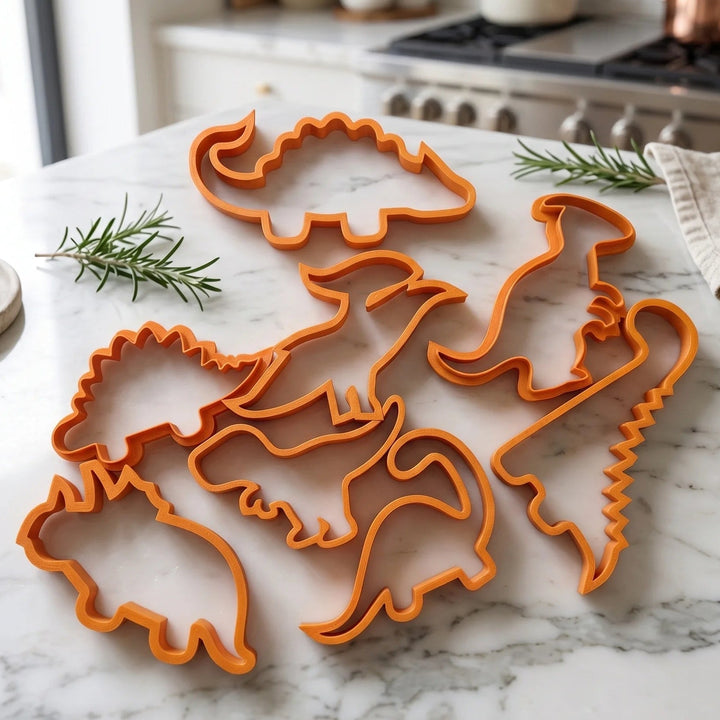 Set of dinosaur cookie cutters in orange on a kitchen countertop.
